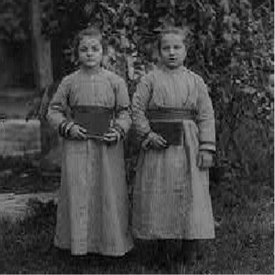 Detail: Black and white photograph of two girls in dresses standing in front of a tree