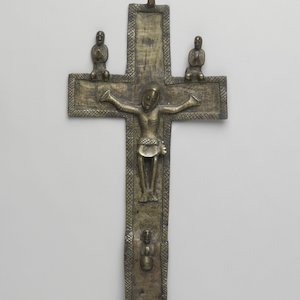 Copper-alloy cast crucifix, with two kneeling figures resting on bar above hands, with a third projecting below the central figure's feet.