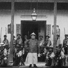 Photograph of about 20 soldiers posing in front of a building